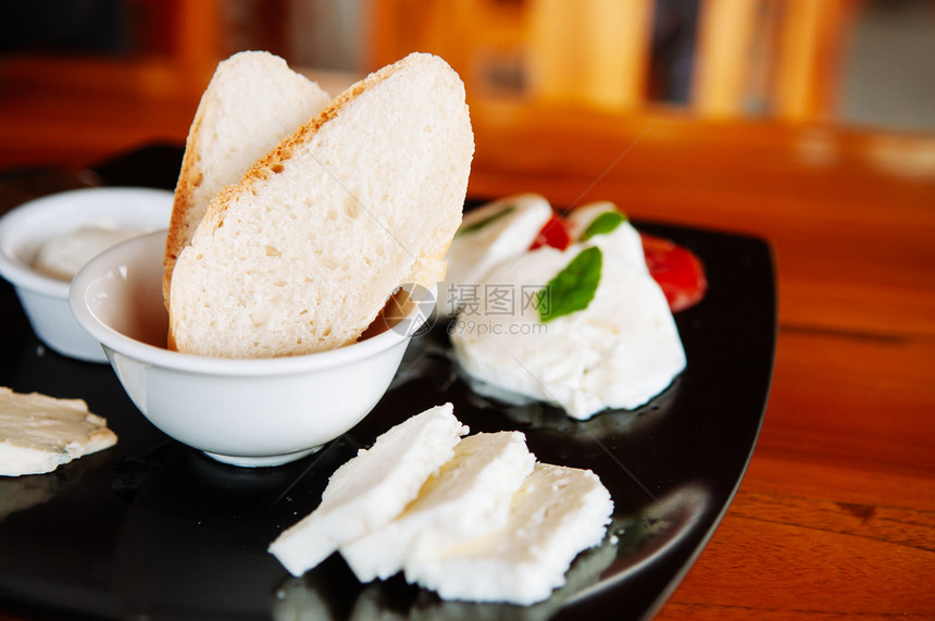 面包切片新鲜马扎里拉奶粉和黑盘中各种水牛奶酪图片
