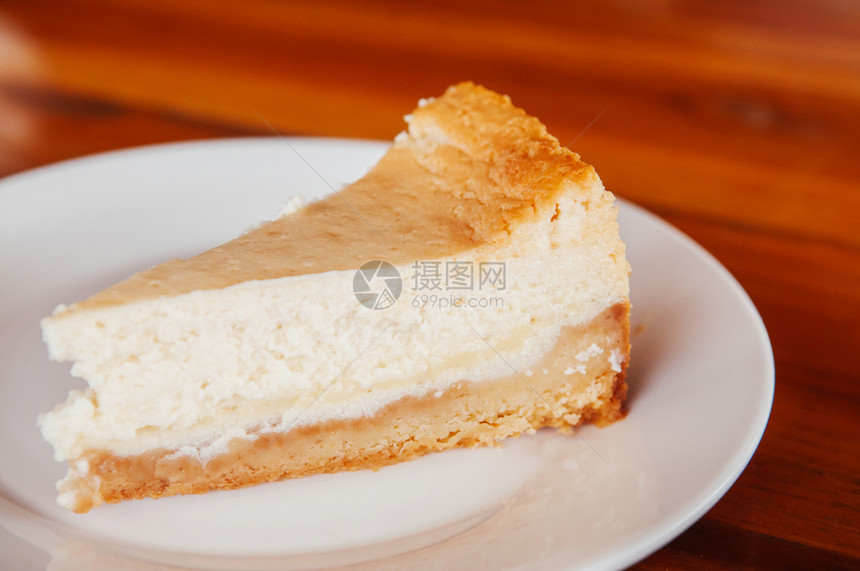 白板上的新鲜烤面包奶酪饼放在木板上的白盘子关闭整个馅饼美丽的奶酪蛋糕层图片
