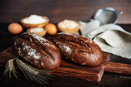 黑麦自制面包灰色餐巾纸面粉和木碗鸡蛋小吃中的粮食有两块黑木背景图片