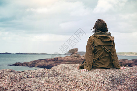 女孩旅行者坐在靠近海边的滩上高清图片