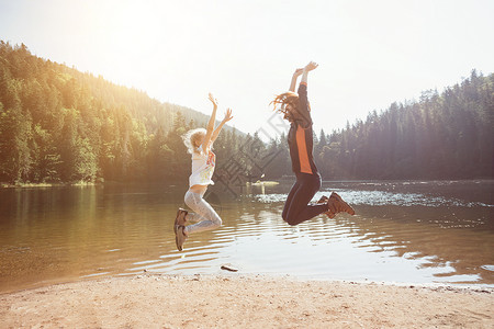 快乐的家庭跳上山湖合欢的海岸背景图片