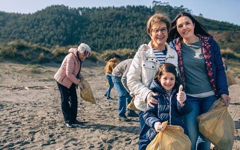 三代女志愿者在海滩打扫的肖像图片