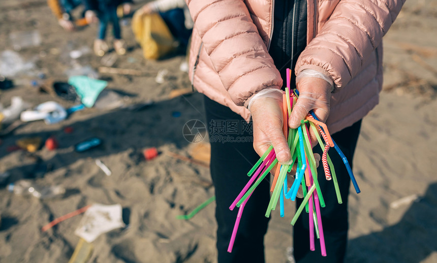 爷爷和孙女志愿者在海滩上拾取塑料吸管图片