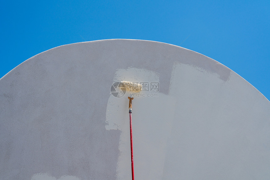 在桑托里尼由滚机对传统房屋施用白漆图片