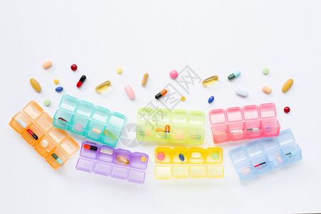 许多彩色平板药片和胶囊带有在白色背景上隔离的药丸盒图片