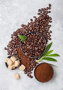 新鲜生有机咖啡豆地面粉和甘蔗糖有咖啡树叶放在轻便厨房桌上背景图片