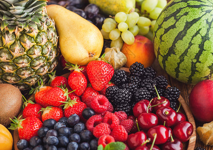 木质盘和本底的外来水果中新鲜有机夏季果子混合物和异国水果草莓蓝黑和樱桃西瓜梨菠萝葡萄背景图片