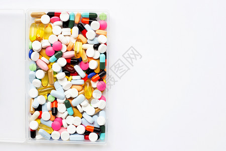 带胶囊和药丸的彩色片装在白背景的塑料盒里背景图片