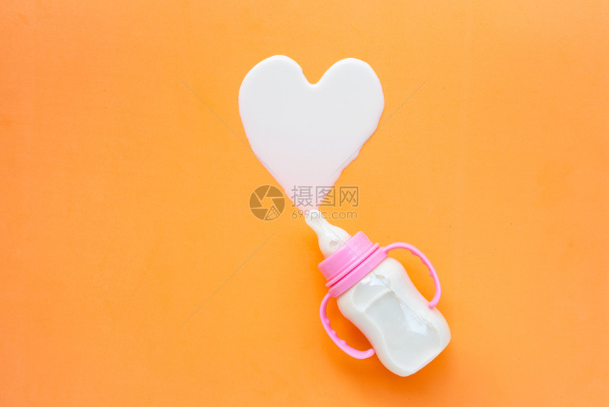 橙色背景的婴儿奶瓶心形状顶视图图片