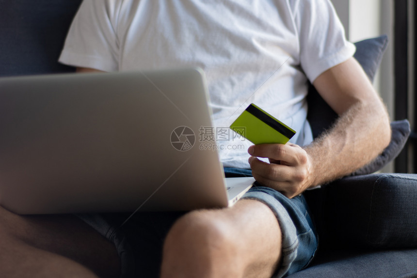 青年男子在家里拥有笔记本电脑和信用卡购物生活方式概念图片