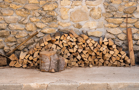 砍碎的木柴和堆在一座生锈的农庄石墙上木柴堆在农庄的石墙上背景图片