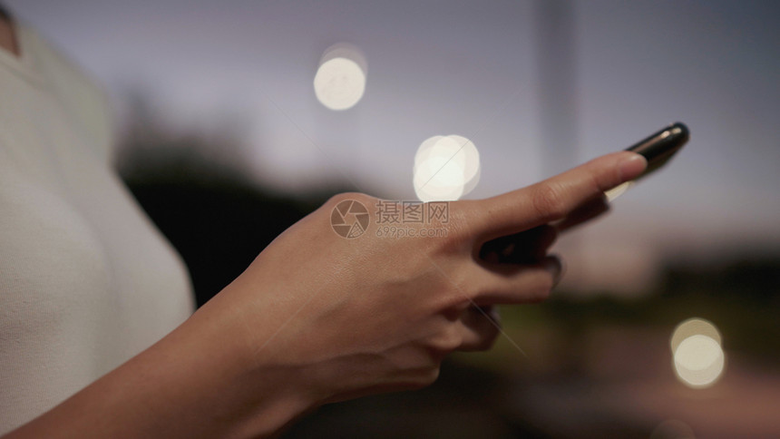 夜里在市中心街上行走时使用智能手机触摸屏技术图片