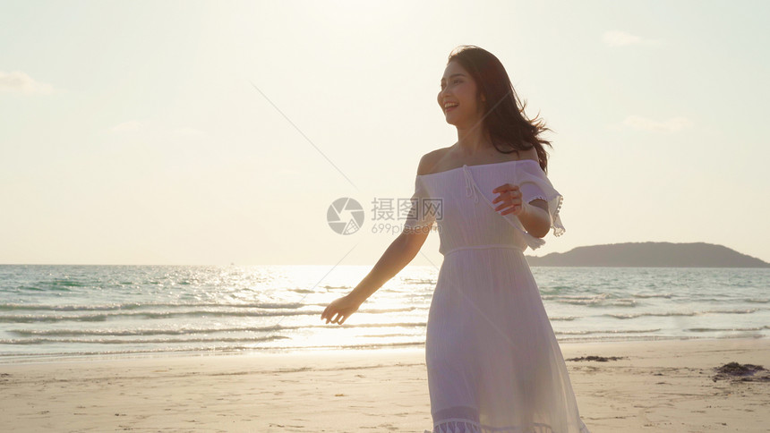 美丽的女快乐放松在晚上日落时海边的滩上行走图片