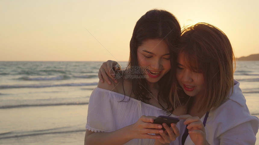 在海滩看手机的两个女孩图片