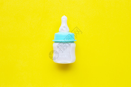 黄色背景下婴儿的奶瓶顶部视图图片
