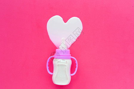 粉红背景的婴儿奶瓶心形状顶视图图片