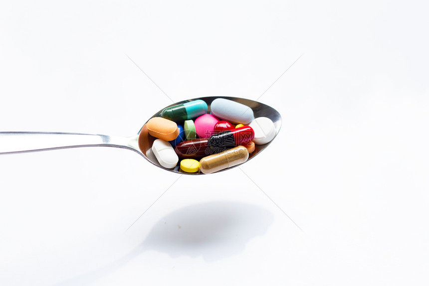 白底勺子上各种类的药片胶和图片