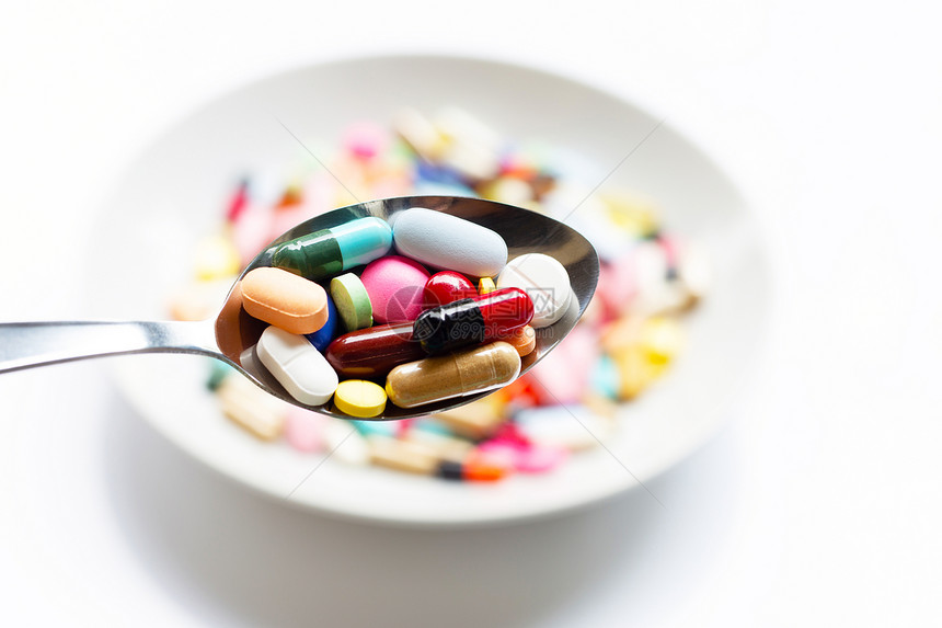 汤匙上各种类的药片胶囊和丸具有丰富多彩的药物背景图片