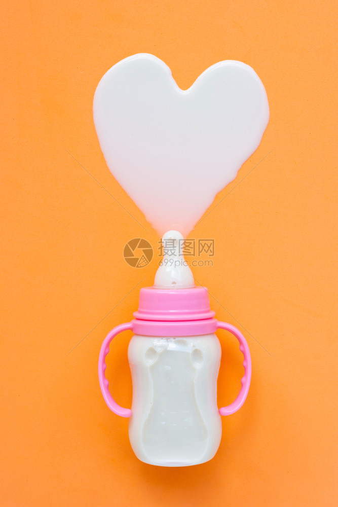 橙色背景的婴儿奶瓶心形状顶视图图片