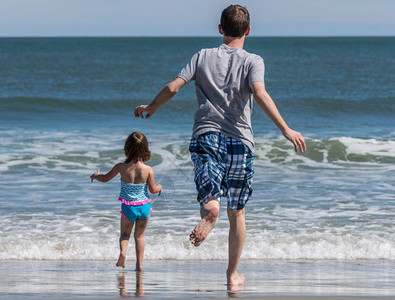 父亲和女儿的兴奋地奔向海面图片