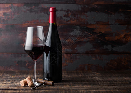 优雅的玻璃和一瓶红葡萄酒里面有木质深本底的软和瓶图片