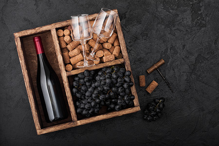 瓶装红酒和空杯子有深葡萄黑色石头背景的旧木箱内有软和开瓶器背景图片