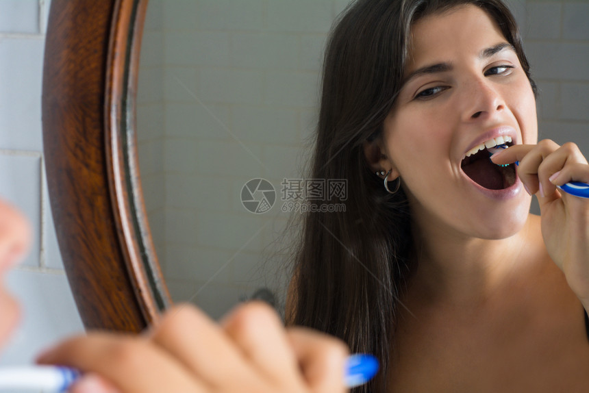 带着牙刷在镜子前的微笑年轻女子保健和口腔卫生概念图片