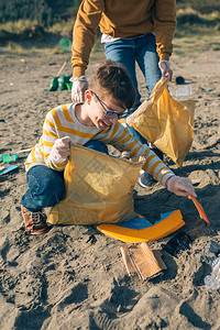年轻志愿者在海滩上捡垃圾图片