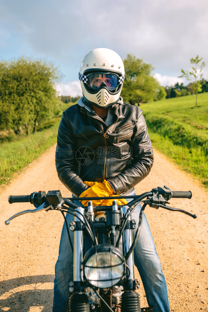 戴头盔的年轻人在户外特制摩托车上骑着头盔的普通摩托车图片