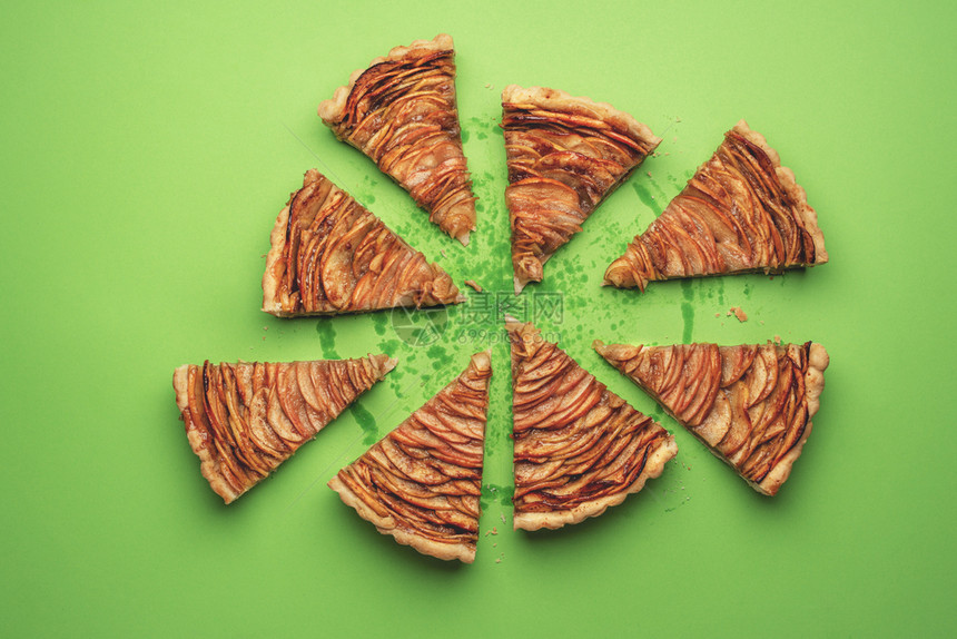 在绿色纸面背景上切成碎片的苹果派在美式味派的视图上部分自制的秋天甜点的糕物品平铺图片