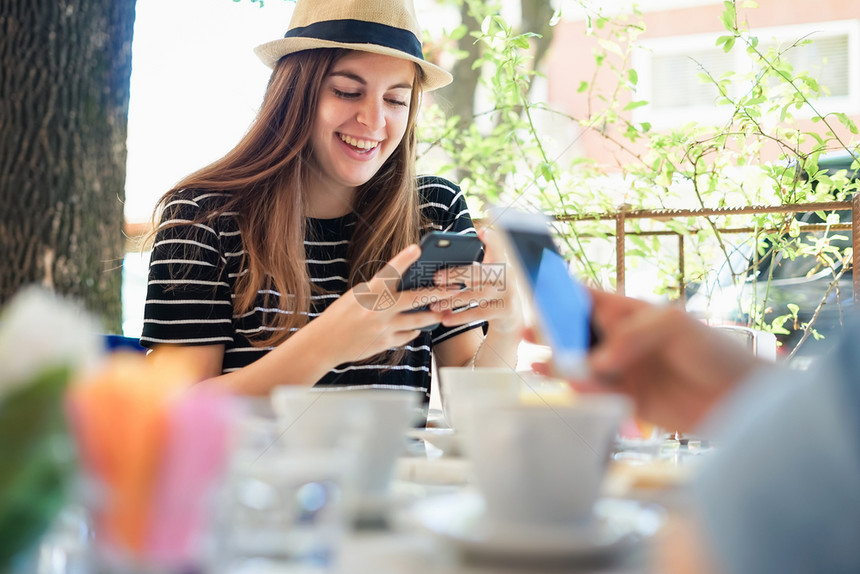 在咖啡店使用智能手机的朋友团体交流概念图片