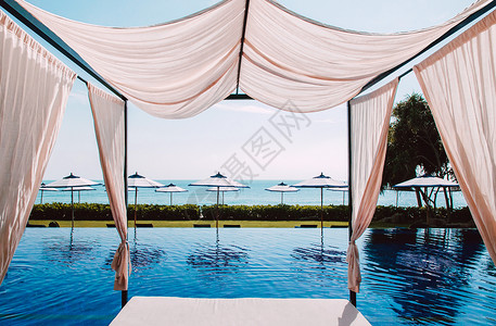 Nov25018samuithlnd带沙滩床的无穷海泳池带窗帘和白色雨伞的沙滩加佐波夏季热带度假胜地概念背景图片
