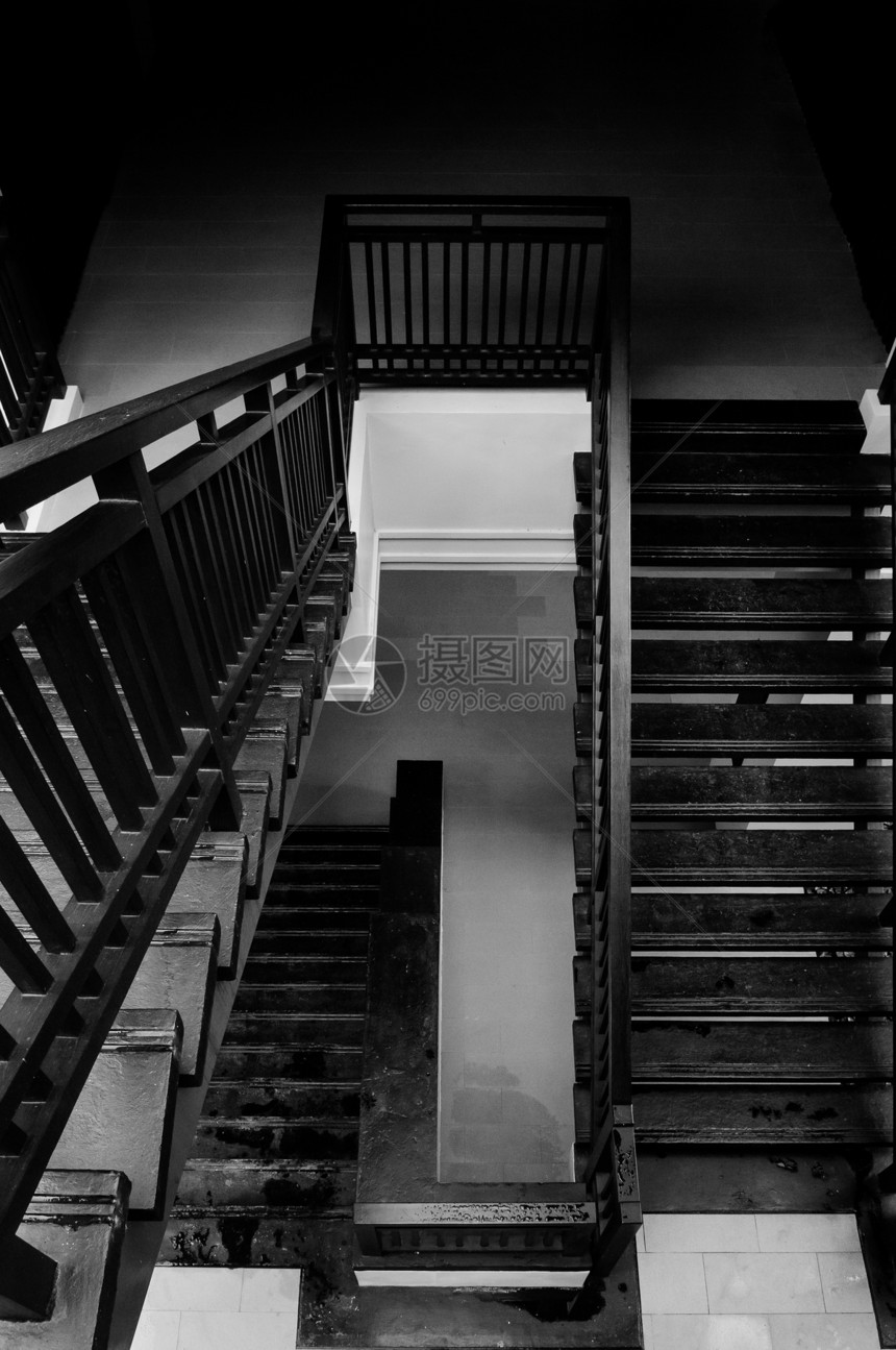 现代简单的黑螺旋楼梯从顶部向下由白墙拍摄黑暗阴影单色内建图案图片