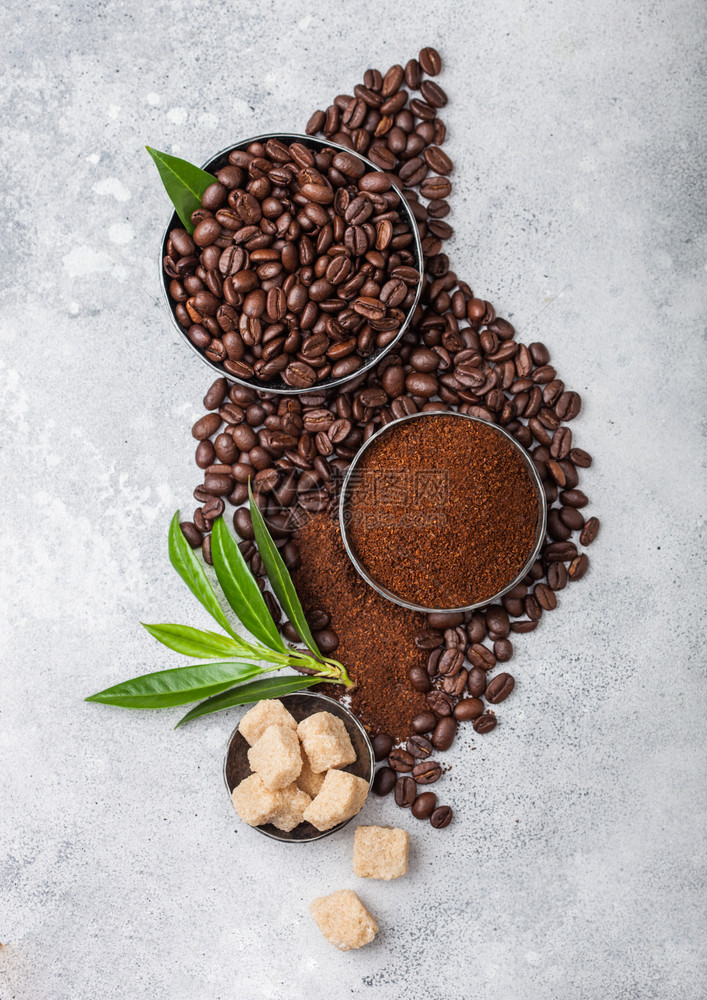 新鲜生有机咖啡豆地面粉和甘蔗糖有咖啡树叶放在轻便厨房桌上图片