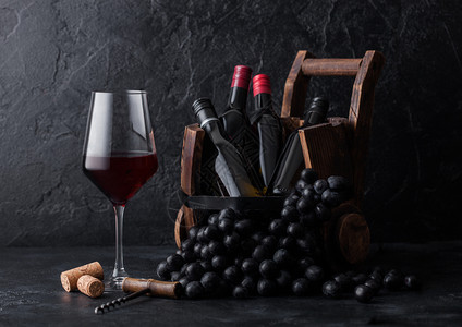 一杯优雅的红葡萄酒深和小瓶在古老木桶里图片