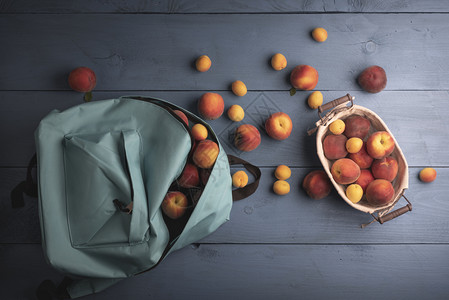 学校背包蓝桌的有机水果金属篮子的成熟桃和杏图片