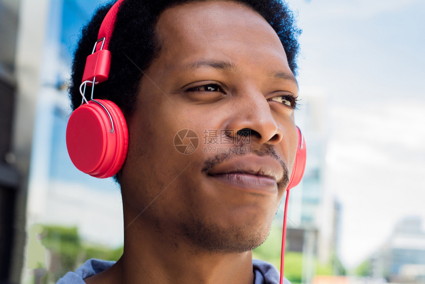 年轻拉丁男子在城里用耳机听音乐享受概念图片