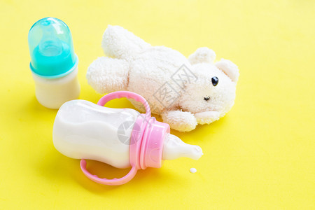 黄色背景上的玩具白熊和婴儿奶瓶图片