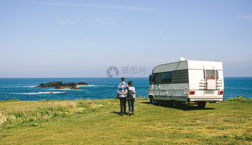 一对夫妇驾驶野营房车车在海岸边散步图片
