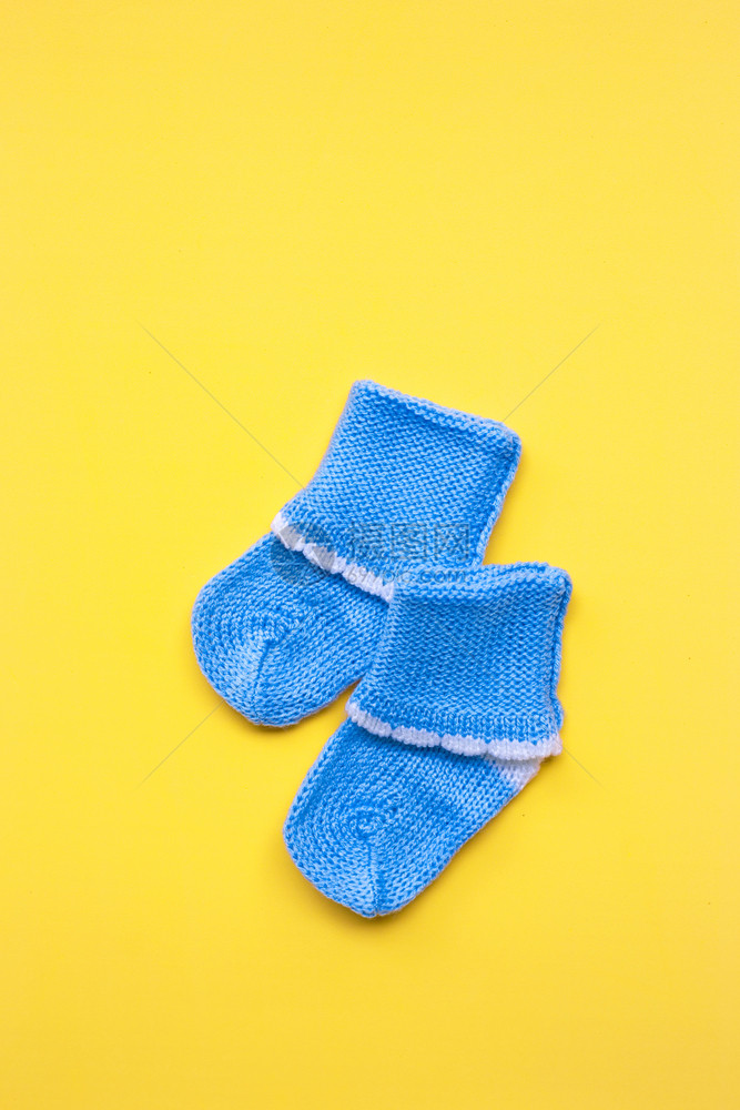 黄色背景的婴儿袜子顶部视图图片