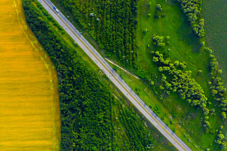 穿越绿色和黄夏季田地的高速公路空中航向图片