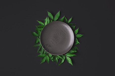 黑色背景的空白灰板周围是绿叶子平整的空盘子食品模拟概念空的餐具和复制间背景图片