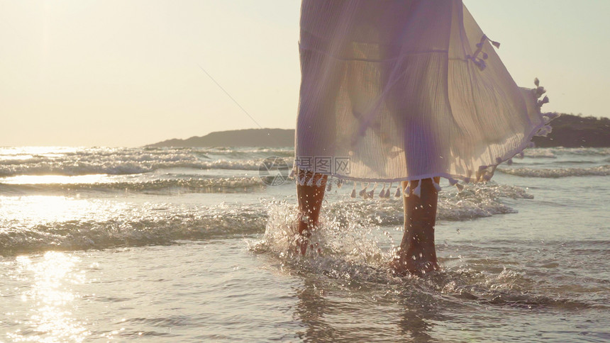 美丽的女快乐放松在晚上日落时海边的滩上行走图片