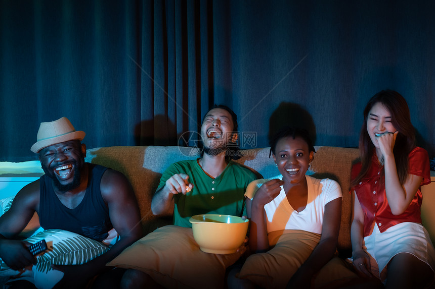 坐在沙发上的朋友一起看电视在家里的夜光环境背景中图片