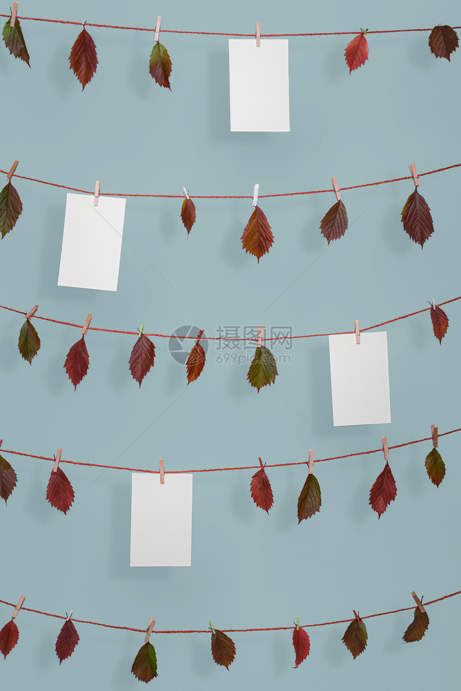 秋天背景有色彩多的落叶挂在绳子上空白纸有木片在蓝色墙上秋天框架有复制空间图片