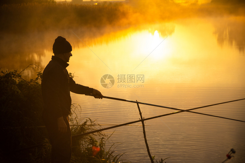 孤单的渔民在金色日出后清晨在雾中湖里游荡图片