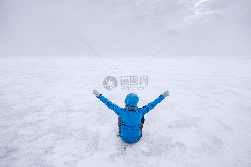 穿外套的女人独自坐在冰湖上图片