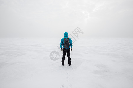 一个人背着包独自站在湖冰上望着前方寒冷的冬天看着前方图片
