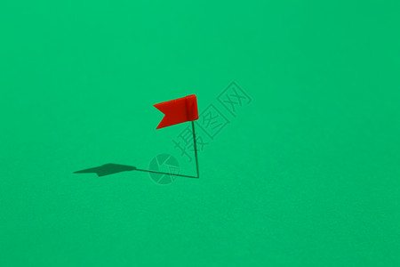 红小旗钉在绿色背景上商业概念图片