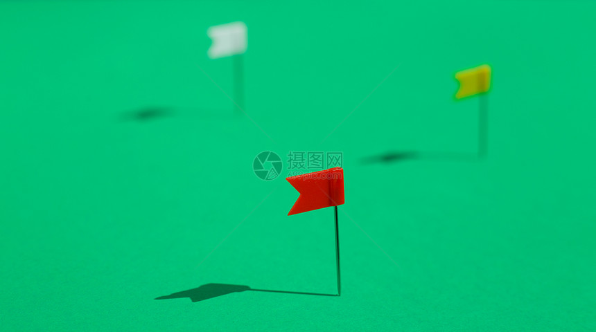 三个有色小旗针钉在绿表面商业或旅行概念目标图片